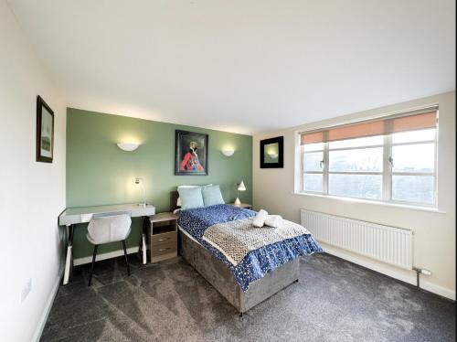 a bedroom with a bed and a desk and a window at Suitely Museum Residence with roof terrace in Ipswich