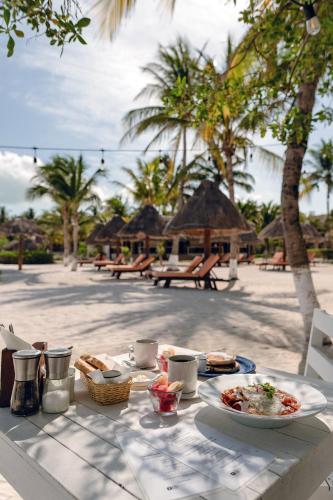 uma mesa com um prato de comida na praia em Hotel Puerto Holbox Beach Front em Ilha Holbox
