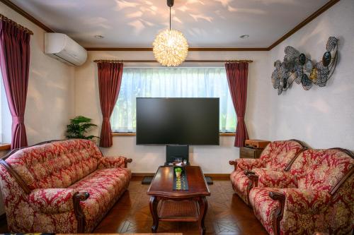a living room with two couches and a flat screen tv at 中山宿 Nakayama Villa 車移動に便利な広島高速すぐそば165平米の贅沢空間 無料駐車場に充電スタンド有り supported by COCOSTAY in Hiroshima