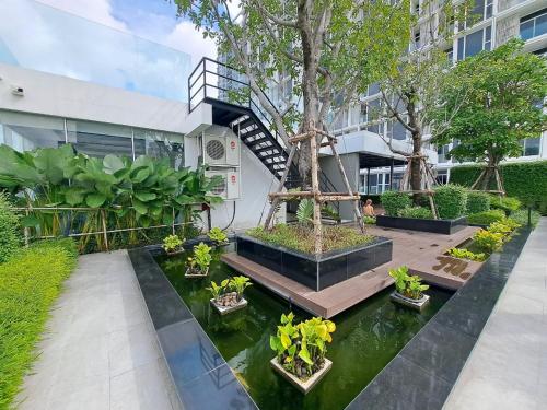 a garden with a pond in front of a building at Stylish 1BR Condo by BTS Ekkamai - Infinity Pool & Gym in Khlong Toei