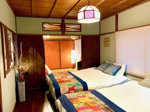 a bedroom with two beds and a pendant light at TSUDOYA Tsukamoto 集家塚本 in Osaka