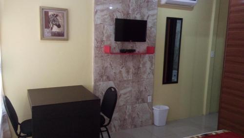 a room with a table and a tv on a stone wall at Hotel Boutique Malibu Los Sueños in Tigre