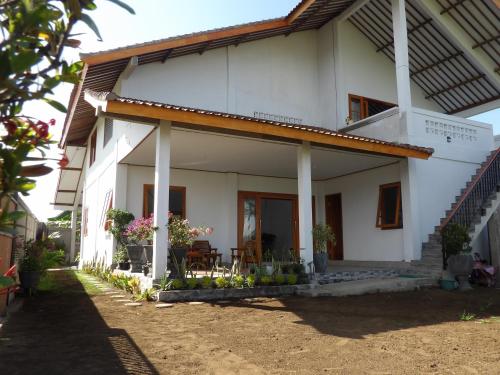 a white house with a porch and a patio at Geyu House in Jembrana