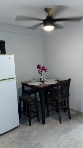 a dining room table with a ceiling fan and flowers on it at Praderas in Los Mochis