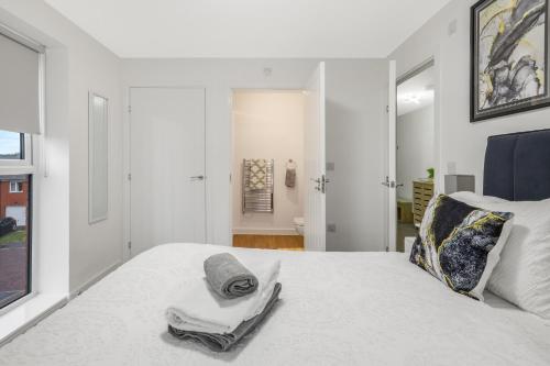 a white bedroom with a bed with towels on it at Beaver Stays- Coventry Serviced Apartment in Coventry