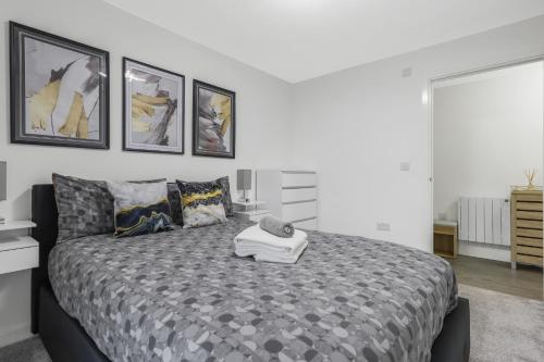 a bedroom with a large bed with four pictures on the wall at Beaver Stays- Coventry Serviced Apartment in Coventry