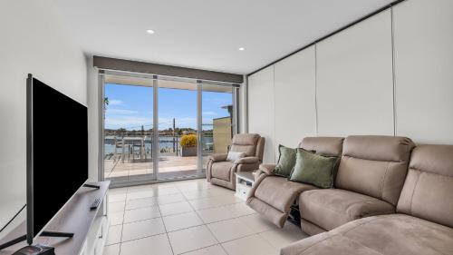a living room with a couch and a flat screen tv at Waterfront On Market in Merimbula