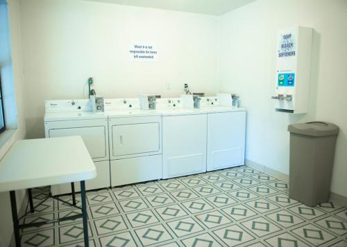 a white bathroom with three sinks and a table at Motel 6-Palestine, TX in Palestine