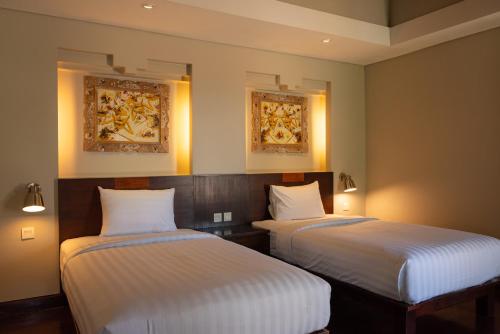 two beds in a room with paintings on the wall at Bali Ula Villa in Nusa Dua