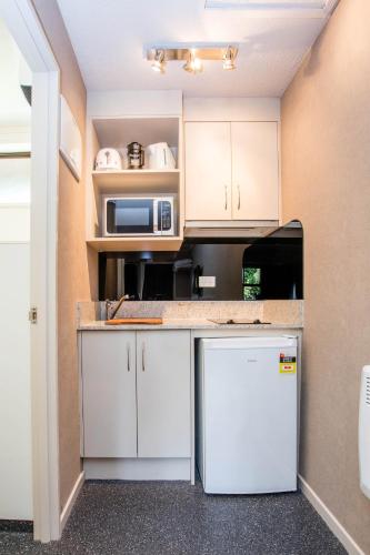 a kitchen with white cabinets and a refrigerator at Te Anau Top 10 Holiday Park and Motels in Te Anau