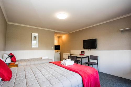 a bedroom with a bed and a table and a tv at Te Anau Top 10 Holiday Park and Motels in Te Anau