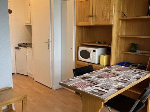 - une cuisine avec une table et un four micro-ondes dans l'établissement Studio cosy pour 2 avec balcon à Plan Peisey - FR-1-757-130, à Peisey-Nancroix