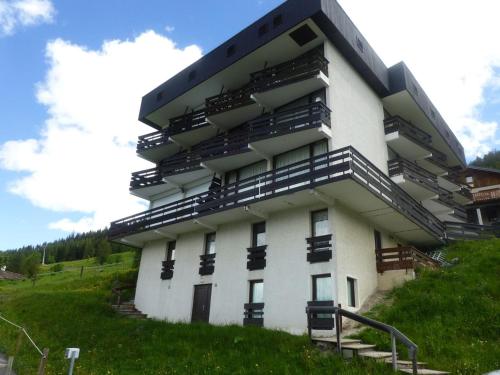 - un bâtiment blanc avec des balcons noirs sur une colline dans l'établissement Studio cosy pour 2 avec balcon à Plan Peisey - FR-1-757-130, à Peisey-Nancroix