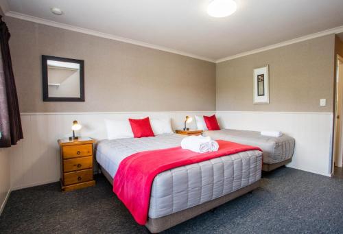a bedroom with two beds with red and white pillows at Te Anau Top 10 Holiday Park and Motels in Te Anau