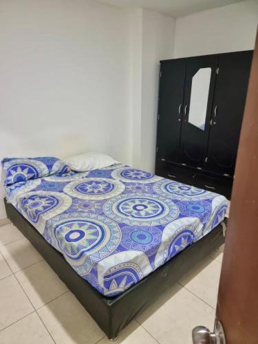 a bed with a blue and white quilt in a bedroom at Hostal tercer cielo Restaurante Fidelio in Santa Marta