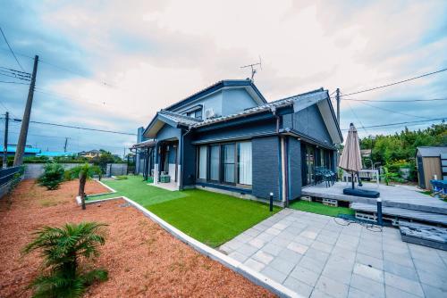 a blue house with a lawn and a patio at 秘密基地白子ベース in Shirako