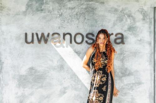 a woman in a dress standing in front of a wall at Uwanosora Bed&BBQ&Sauna in Shizuoka