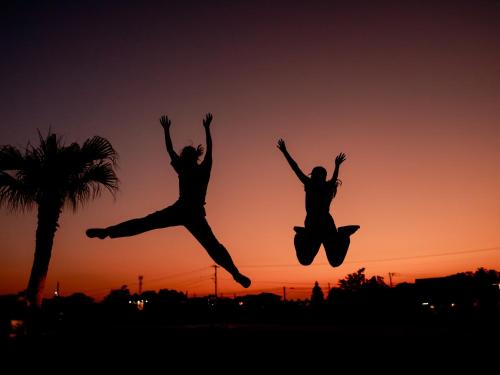 two people jumping in the air at sunset at HARIO Beach Walk in Sakihario