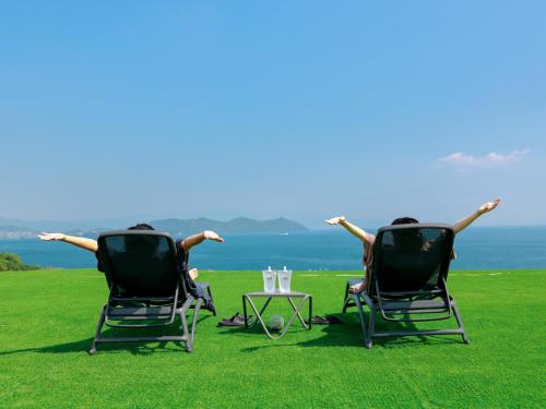 two people sitting in chairs on the grass with a table at HARIO Beach Walk in Sakihario