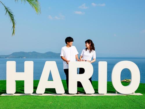 a couple standing next to a large sign that readshare at HARIO Beach Walk in Sakihario