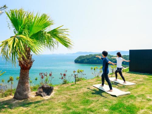 a man and woman standing on surfboards near a palm tree at HARIO Beach Walk in Sakihario