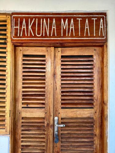 a wooden door with a sign that readshakuna matata at Coconut Mafia Island Bungalows in Utende