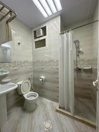 a bathroom with a toilet and a shower and a sink at Al Zahra Hotel Apartments Ras Al Khaimah in Ras al Khaimah