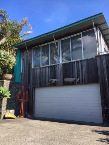 a house with a white garage door with a window at The Nikau Loft in Onetangi