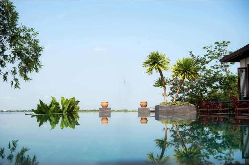 a view of a swimming pool with palm trees at Nghê Prana Hotel and Spa Hoi An in Hoi An