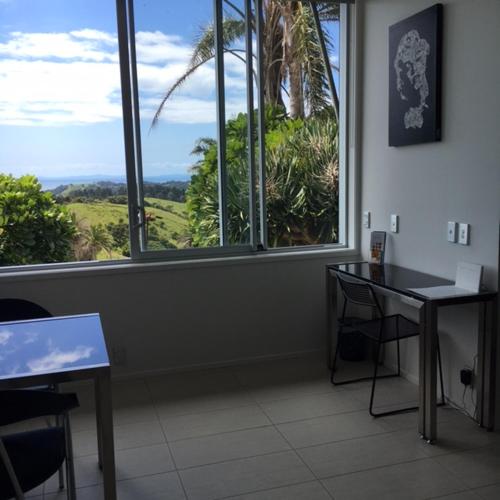 a room with two tables and a large window at The Nikau Loft in Onetangi