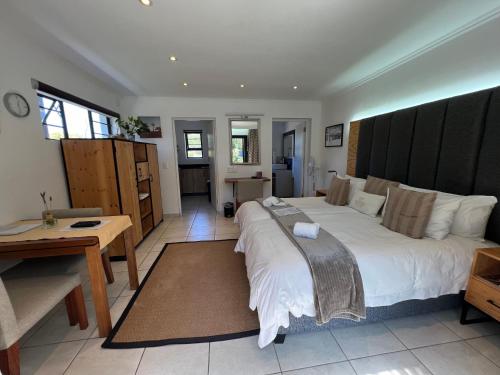 a bedroom with a large white bed and a desk at Pelican Lodge Guesthouse in Sedgefield
