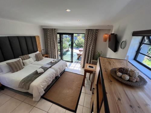 a bedroom with a large bed and a table at Pelican Lodge Guesthouse in Sedgefield