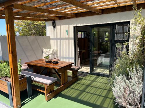 an outdoor patio with a wooden table and chairs at Pelican Lodge Guesthouse in Sedgefield