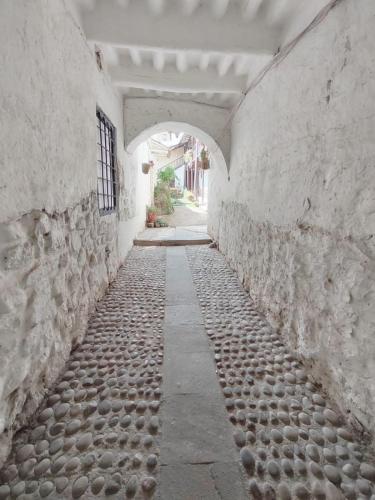 an alley with a stone wall and an archway at Afma Cusco in Cusco