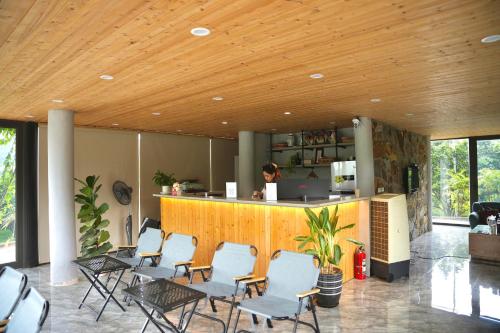 a lobby with chairs and a counter with a person in a kitchen at Ora Hill Retreat in Cao Phong