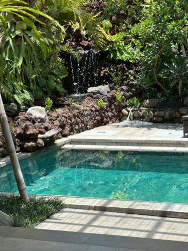 a swimming pool with a waterfall in a garden at Melati bali villa in Canggu