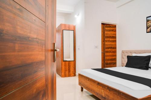a bedroom with a bed and a wooden door at Super Hotel O Neelbad Guest House in Bhopal