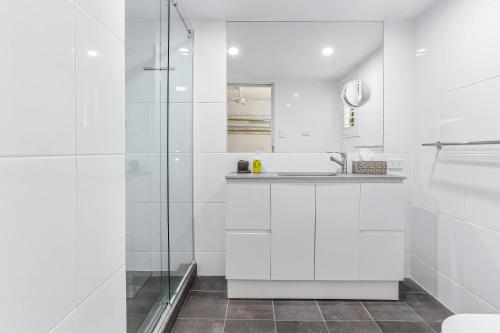 a white bathroom with a sink and a shower at Noosa River Retreat Holiday Apartments in Noosaville