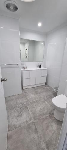 a white bathroom with a toilet and a sink at Noosa River Retreat Holiday Apartments in Noosaville