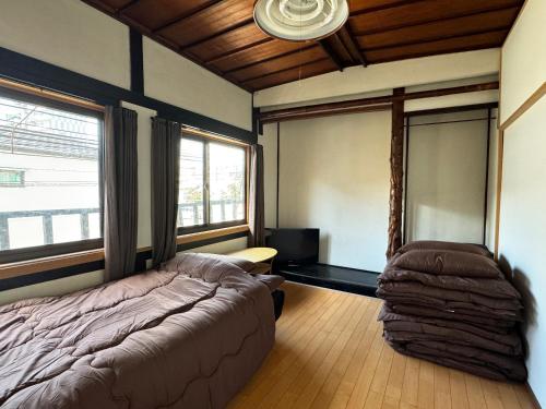 a bedroom with a bed and a chair in it at ゲストハウス千福 in Saga