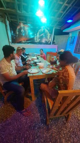 a group of people sitting around a wooden table at TATHASTU Bir -Homestay ,DORM,HOSTEL in Bīr