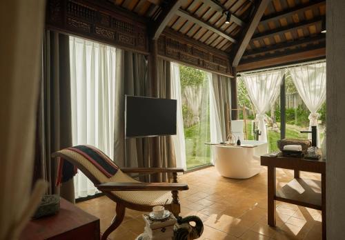 a living room with a tub and a chair and a television at aNhill Boutique in Hue