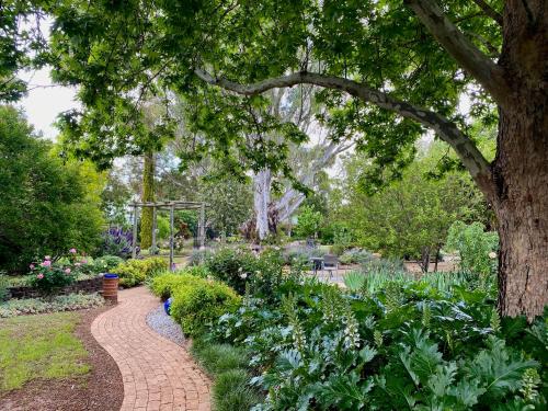 a brick path in a garden with flowers and a tree at The Retreat at Froog Moore Park in Tamworth