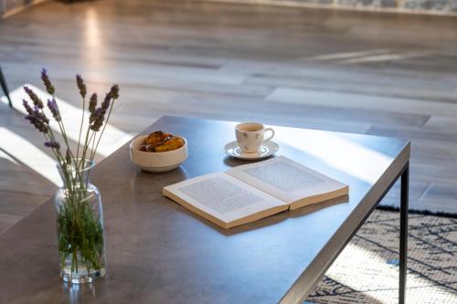 a table with a book and a cup of coffee and a vase of flowers at Manifest Boutique Hotel in Oítilon