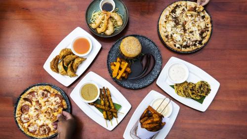a table with different types of food on plates at Mad Monkey Hostel Siem Reap in Siem Reap