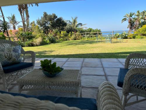 a patio with a table and chairs and the ocean at Beach Melody, Umdloti South Beach, king Bed in Umdloti