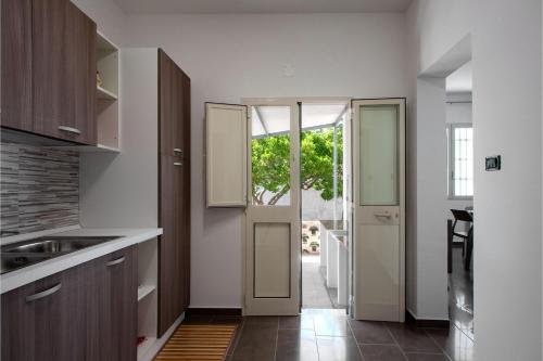 a kitchen with white walls and wooden cabinets and a door at Villa Sabbia Magica 100 meters from sea - Happy Rentals in Porto Cesareo