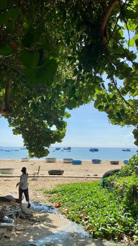 a man standing on a beach near the ocean at Sea For Rest Homestay in Xuân Dục