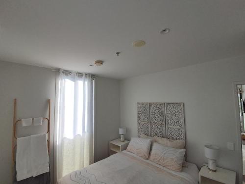 a white bedroom with a bed and a window at Pool-bikes-escooter! 2bed central in Auckland