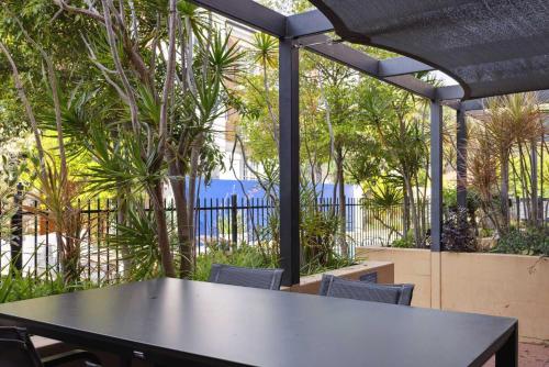 a black table and chairs in a patio with trees at 3BR Oasis Townhouse in Northbridge in Perth